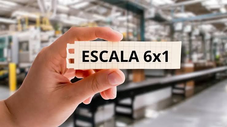 Mão segura papel com texto "ESCALA 6x1" em frente a fábrica.