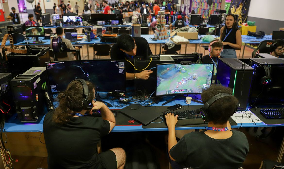 Participantes competem em torneio de jogos eletrônicos durante evento que reúne centenas de jogadores em espaço fechado.