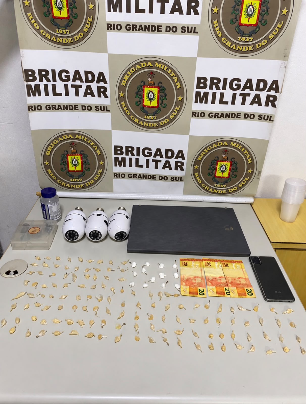 Brigada Militar exibe drogas apreendidas durante operação em Encantado: 127 pedras de crack, cocaína, dinheiro e equipamentos.