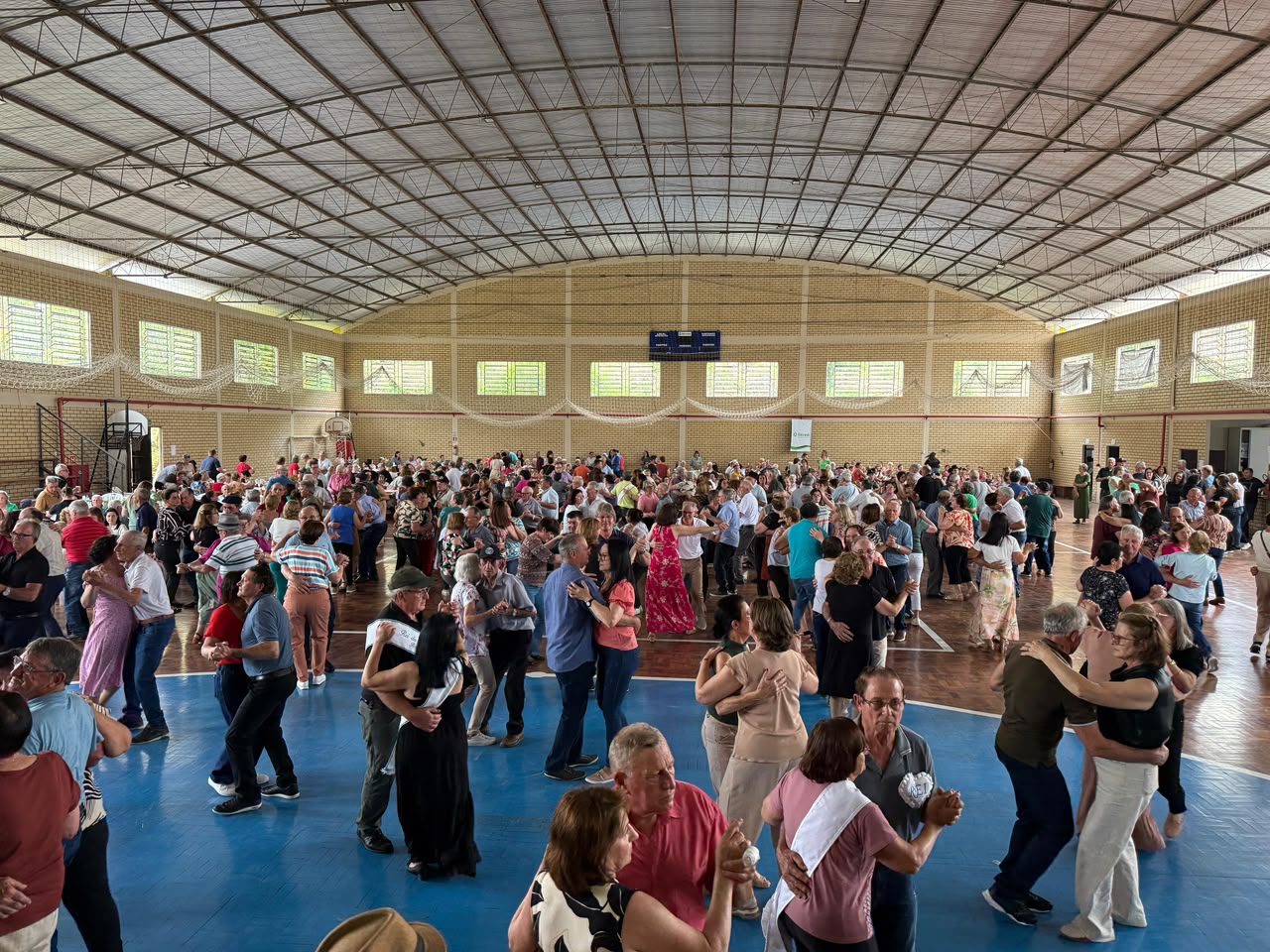Centenas de idosos dançam juntos em ginásio durante baile regional da terceira idade em Relvado.
