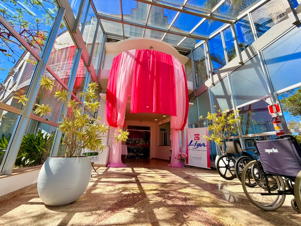 Entrada do Hospital Beneficente Santa Terezinha decorada com cortinas rosa para a campanha Outubro Rosa em Encantado.