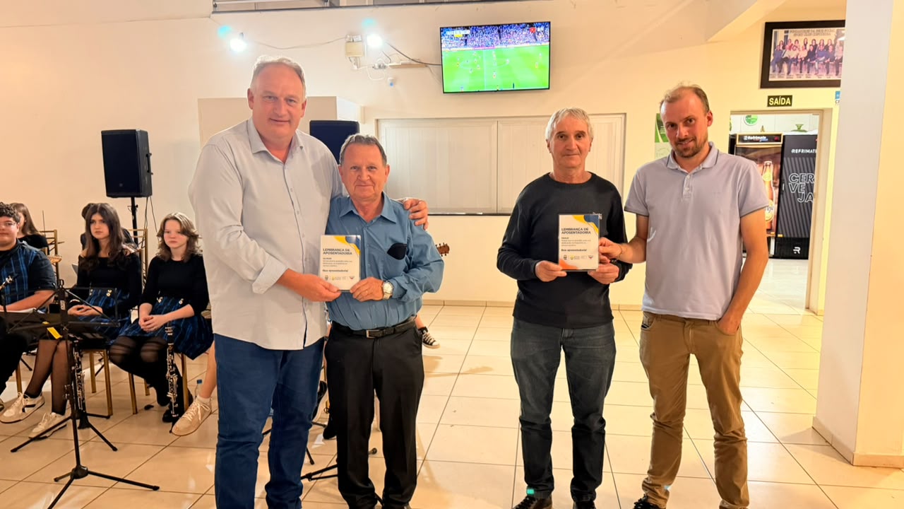 Quatro homens recebem certificados de homenagem durante confraternização de servidores públicos municipais em salão com público ao fundo.