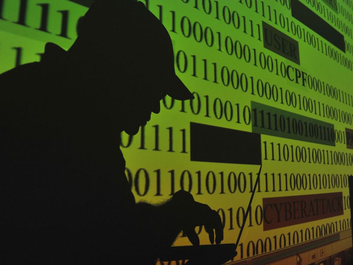 Silhueta de hacker diante de tela com código binário e palavra "cibernético" visível, representando ataque digital à Binance.