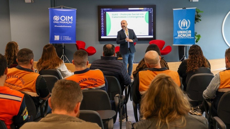 Apresentador conduz treinamento sobre gestão de abrigos em desastres para equipes da defesa civil em Porto Alegre.