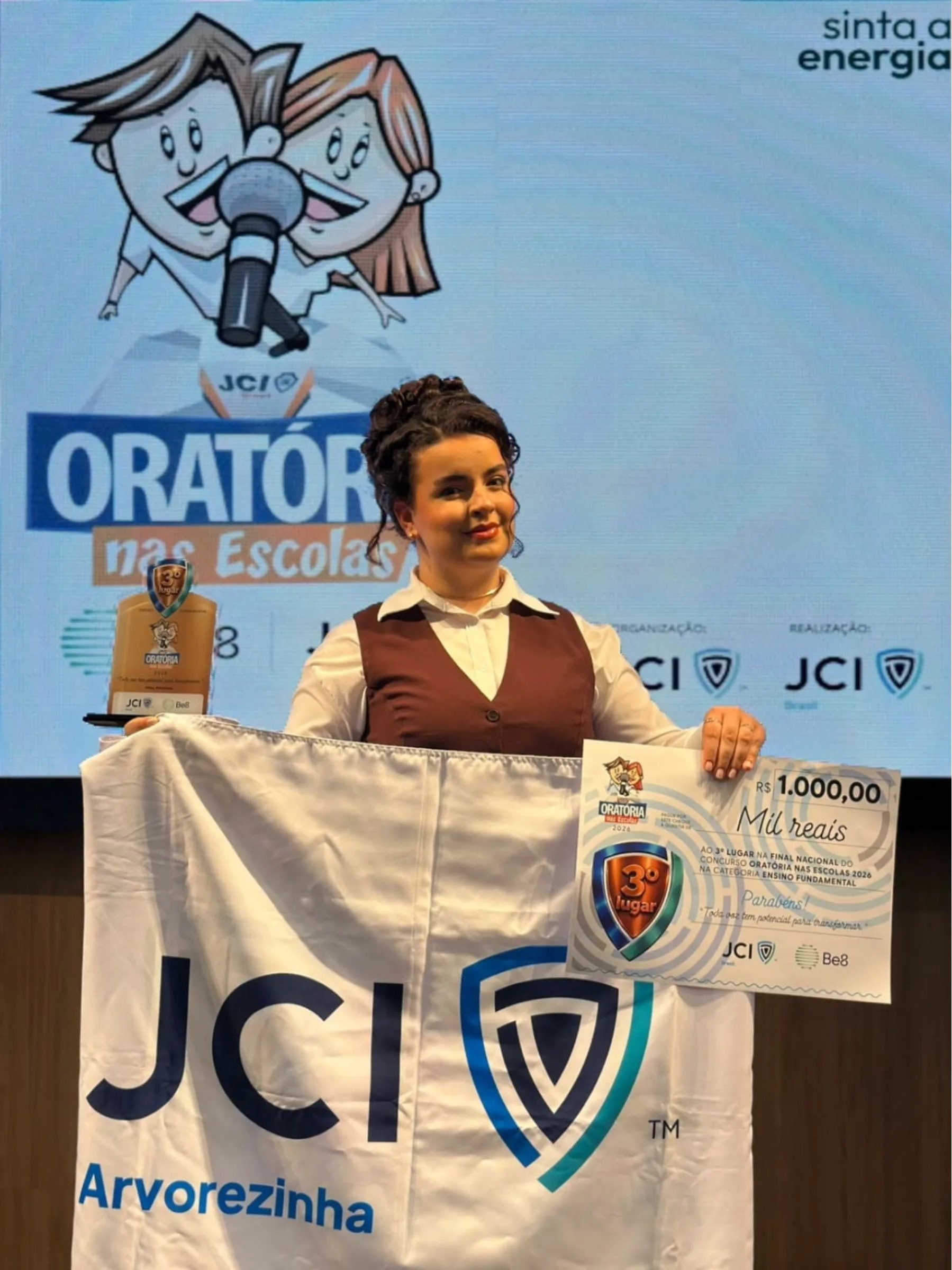 Estudante exibe troféu e certificado de premiação após conquistar terceiro lugar no Concurso Nacional de Oratória nas Escolas.