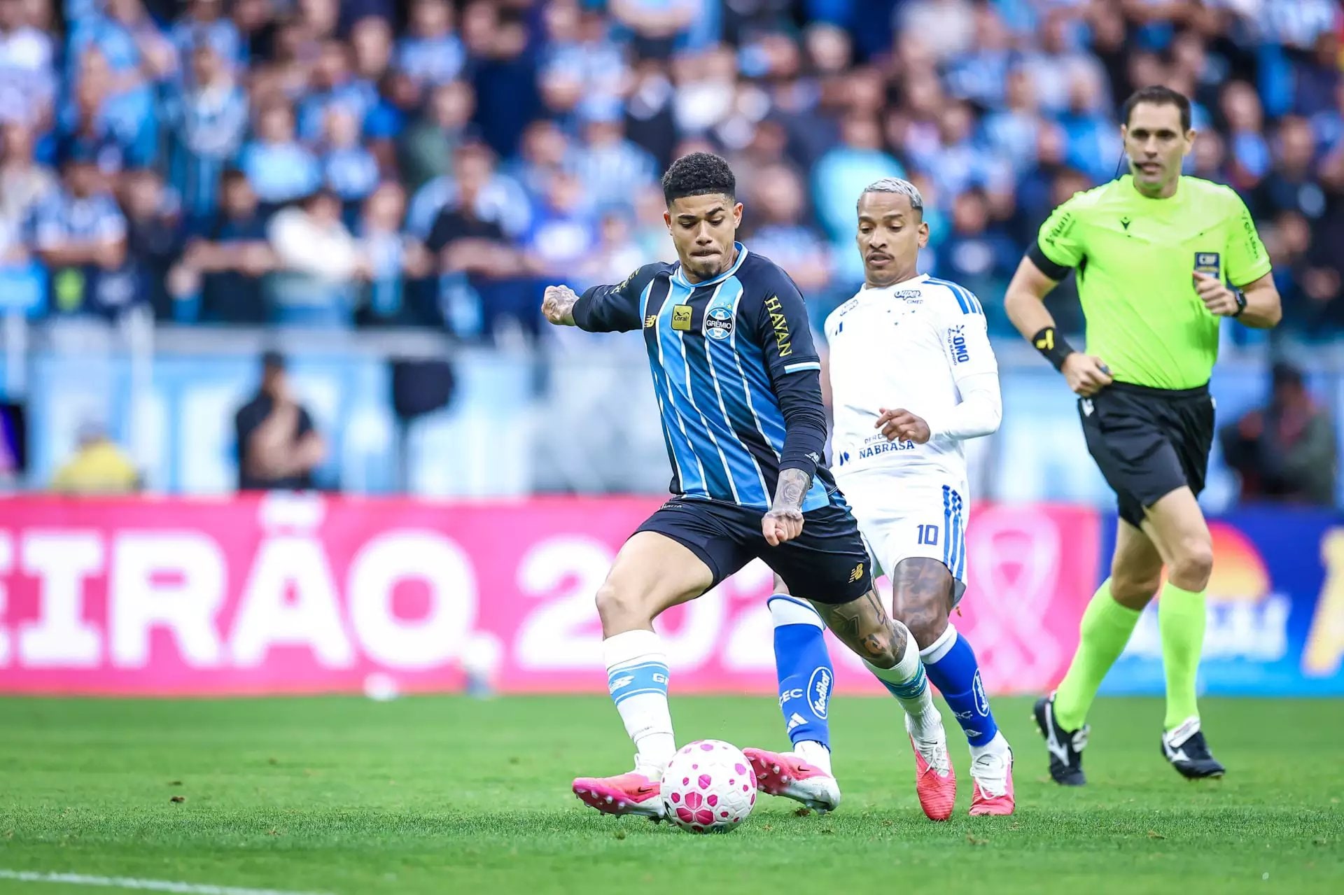 Jogador do Grêmio disputa a bola com adversário do Cruzeiro durante partida na Arena, em Porto Alegre.